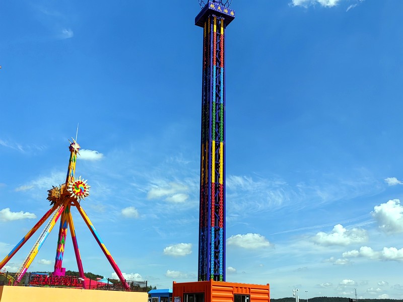 Guests near a drop tower ride at an amusement park